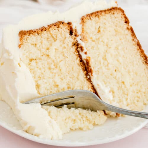 Large slice of white chocolate cake with a fork on a plate.