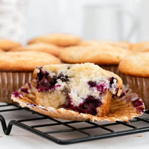Blueberry muffin unwrapped on a rack.