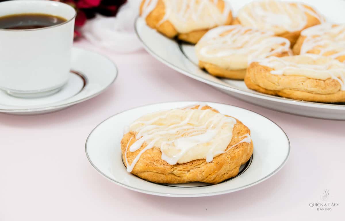 Cream cheese danish with cup of coffee on a plate.