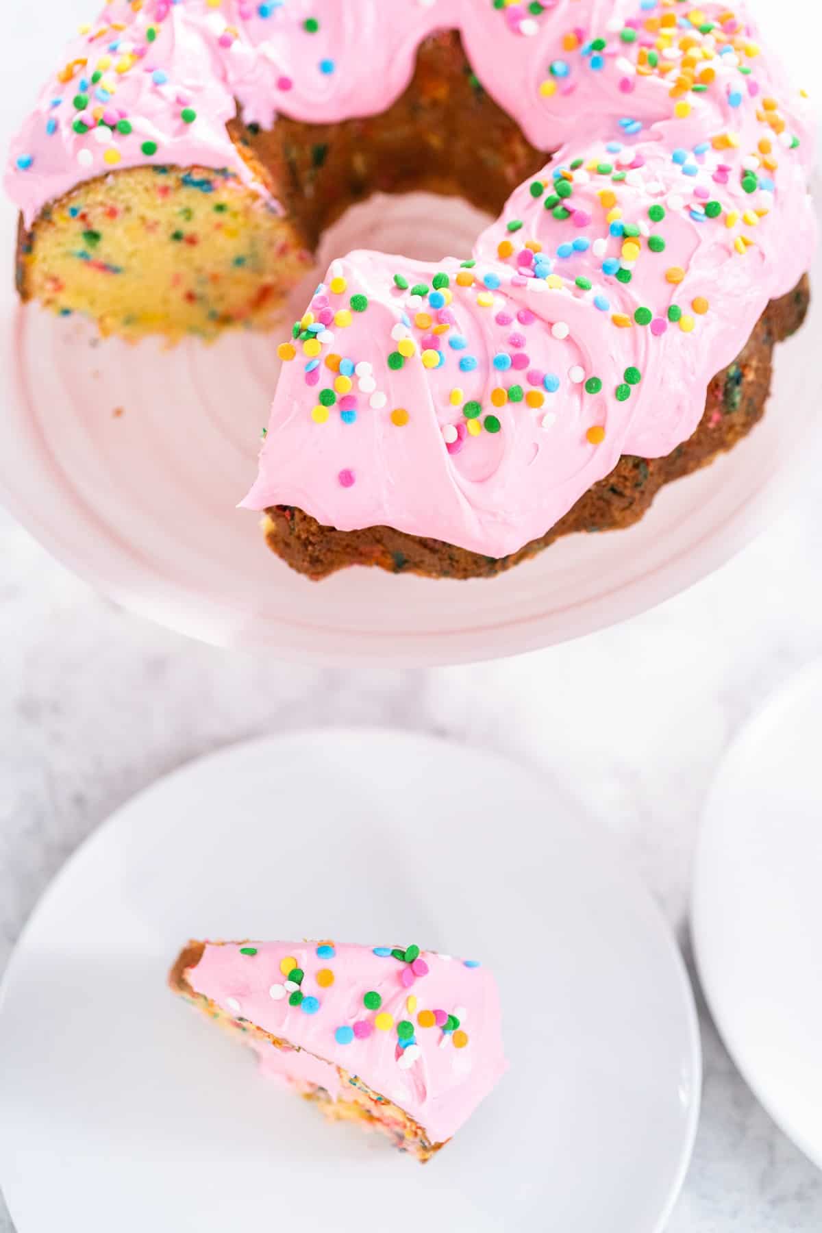 Bundt cake with pink frosting and sprinkles.