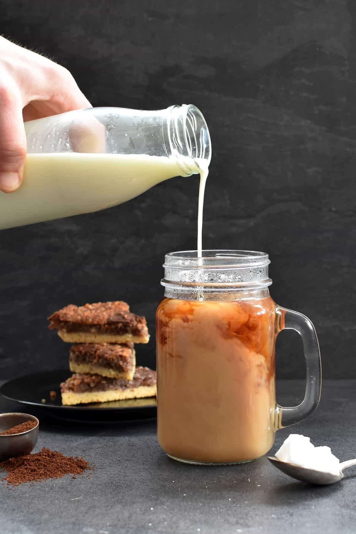 Pouring coffee creamer into drink.