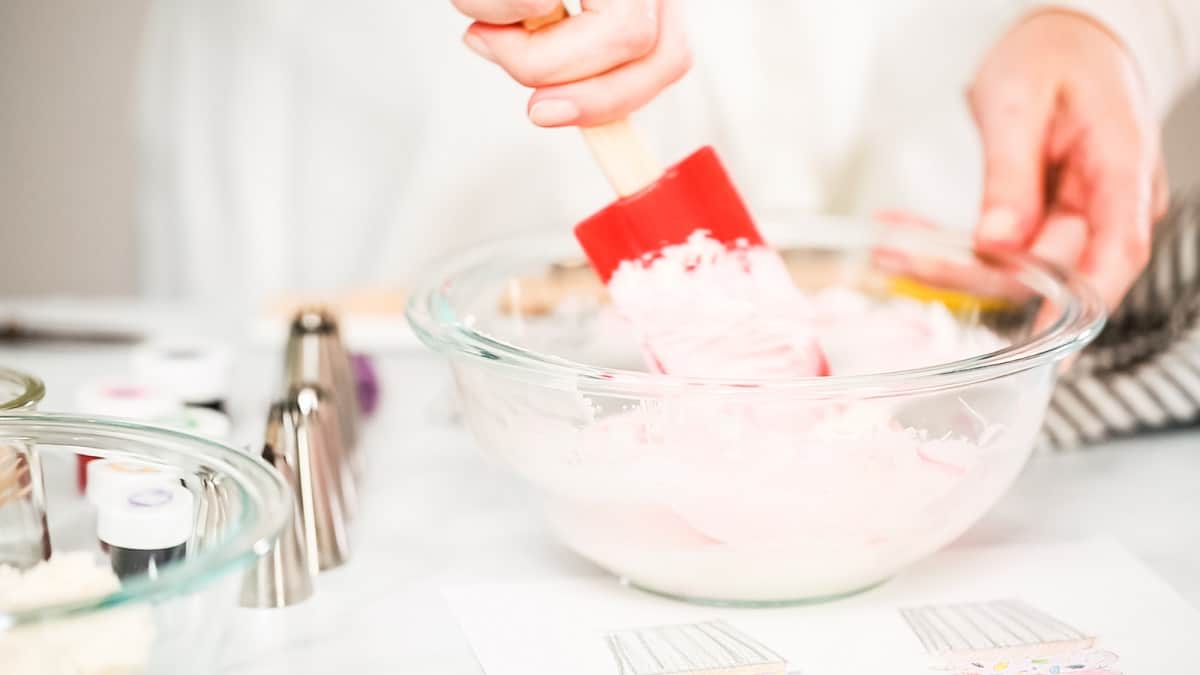 Mixing pink buttercream in a bowl.