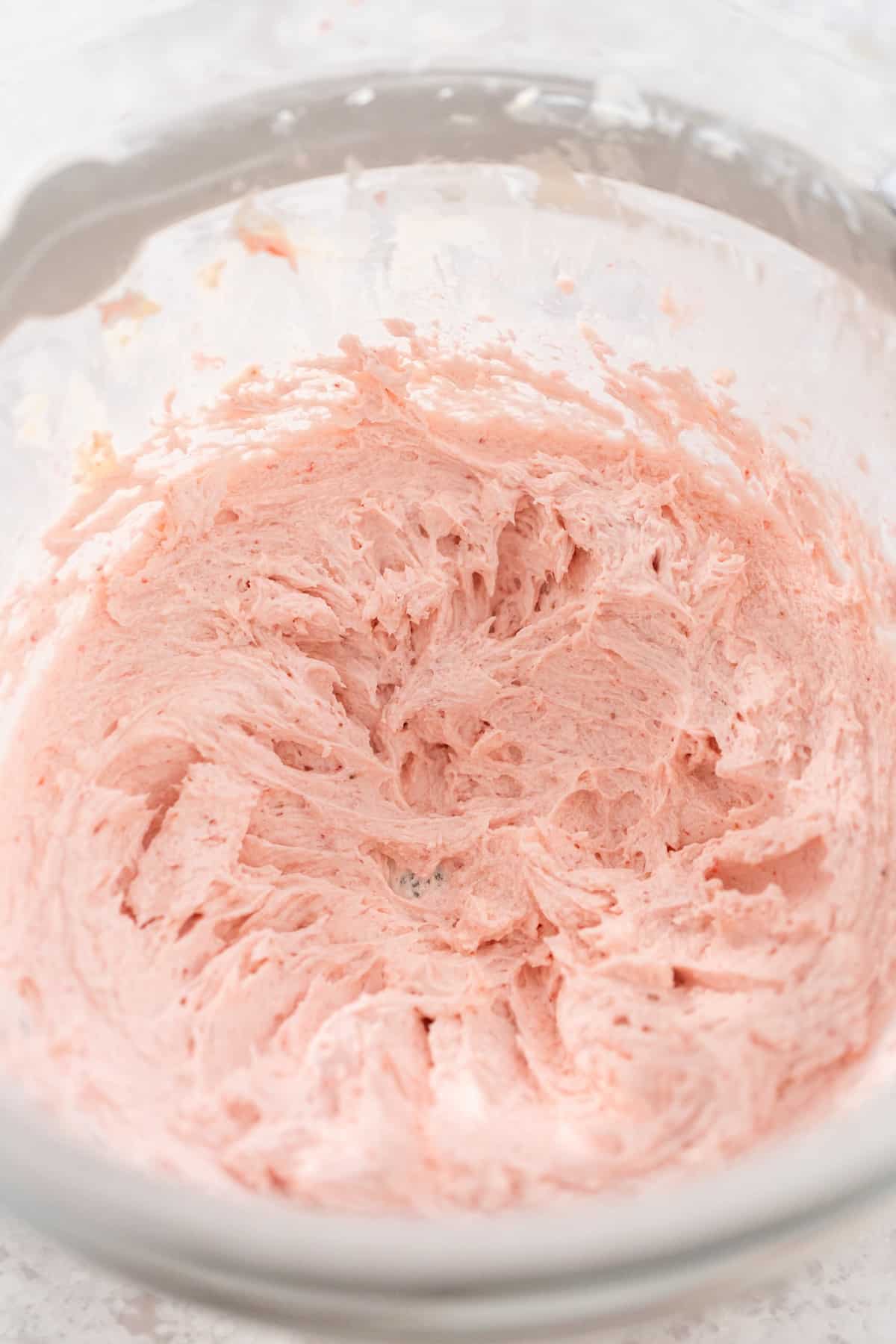 Whipped pink icing in a glass bowl.