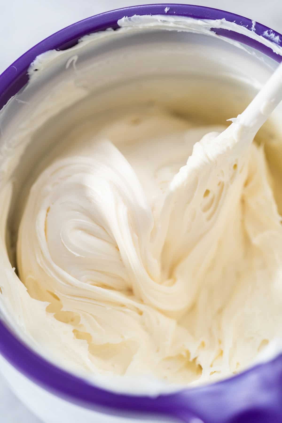 White buttercream in a bowl with spoon.