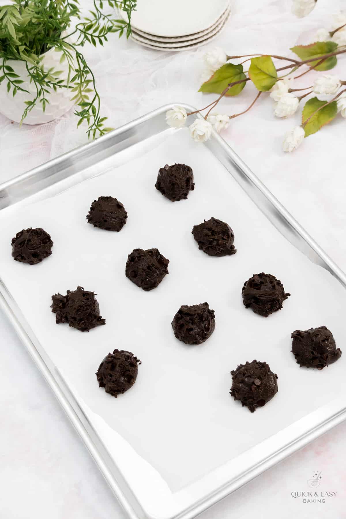 Chocolate mounds of batter on a parchment covered cookie sheet.