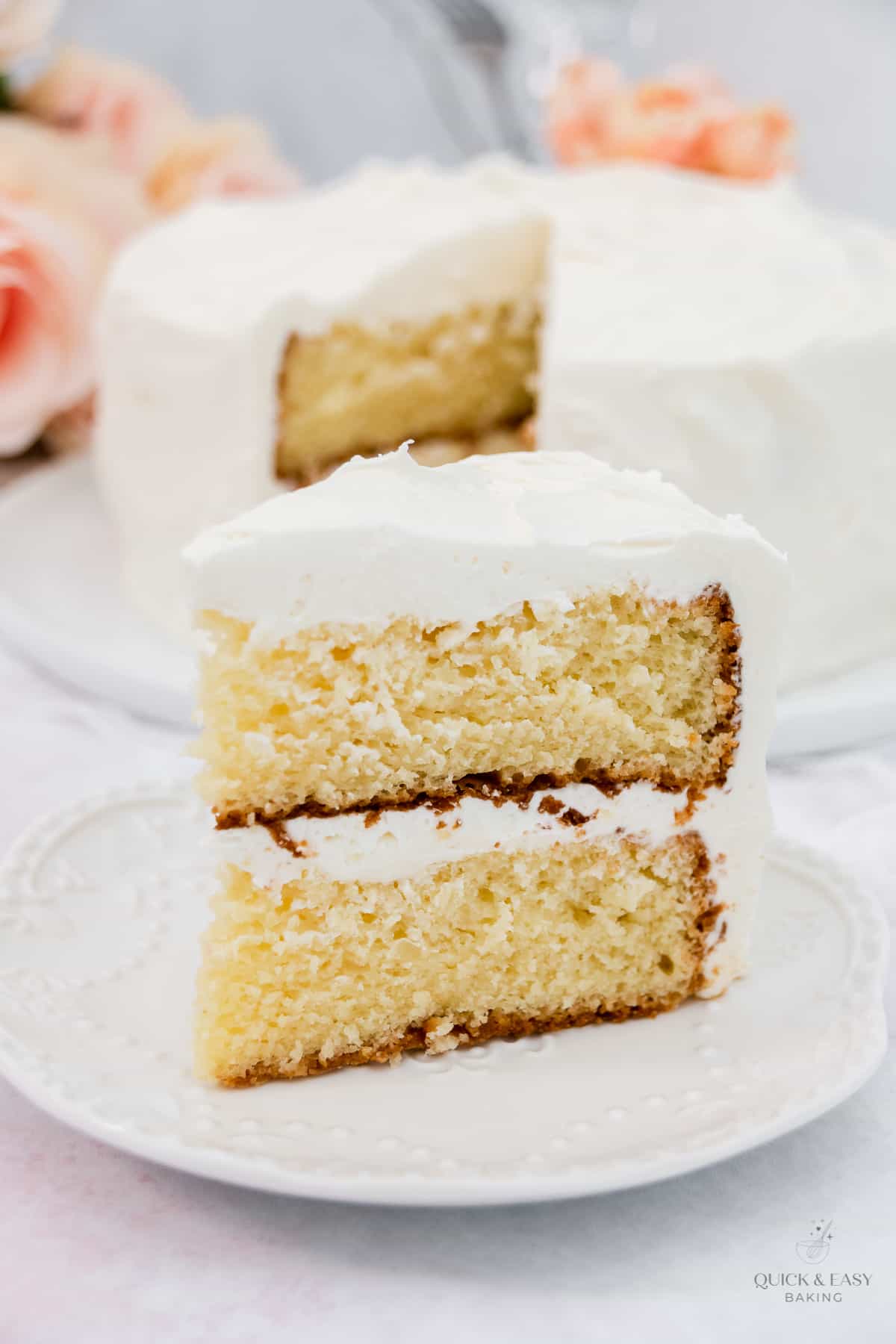 Tall piece of sour cream cake with frosting on a white plate.