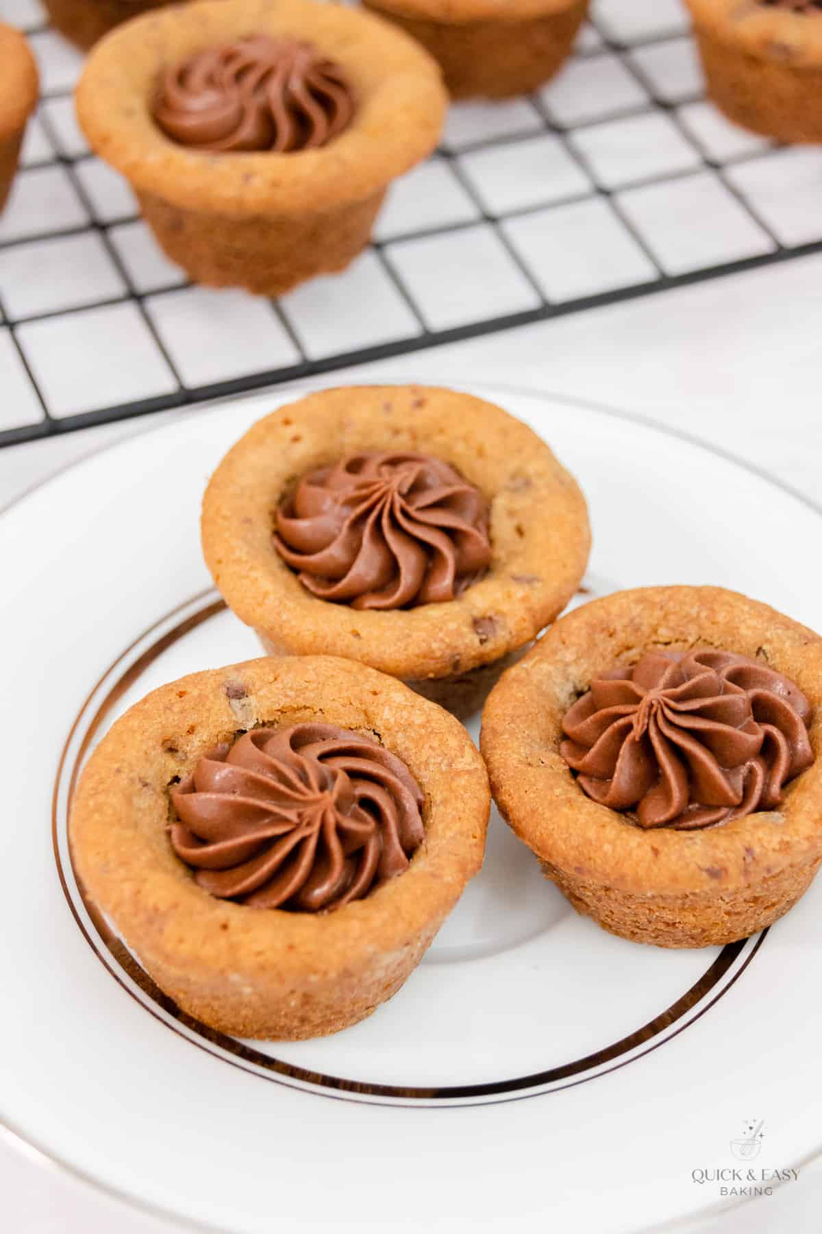 Overhead shot of chewy cookie cups with frosting on a white plate.
