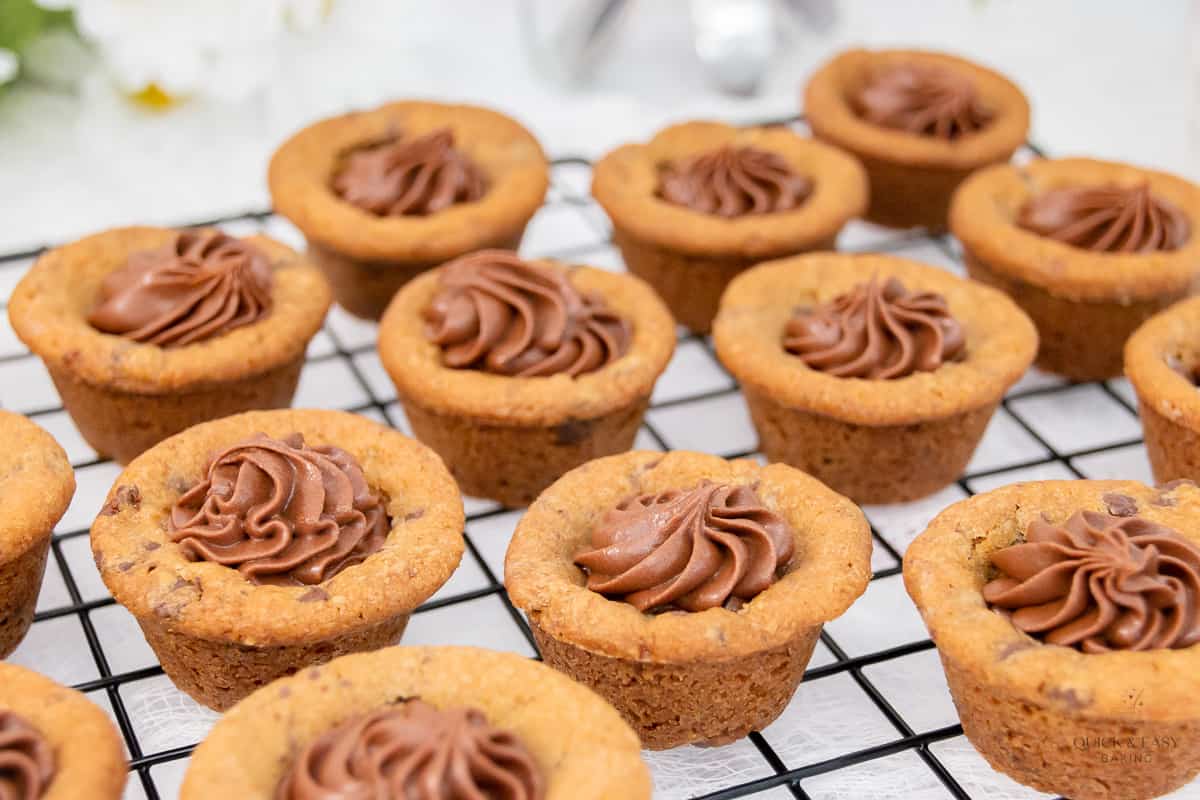Baked chocolate chip cookie cups on a cooling rack.