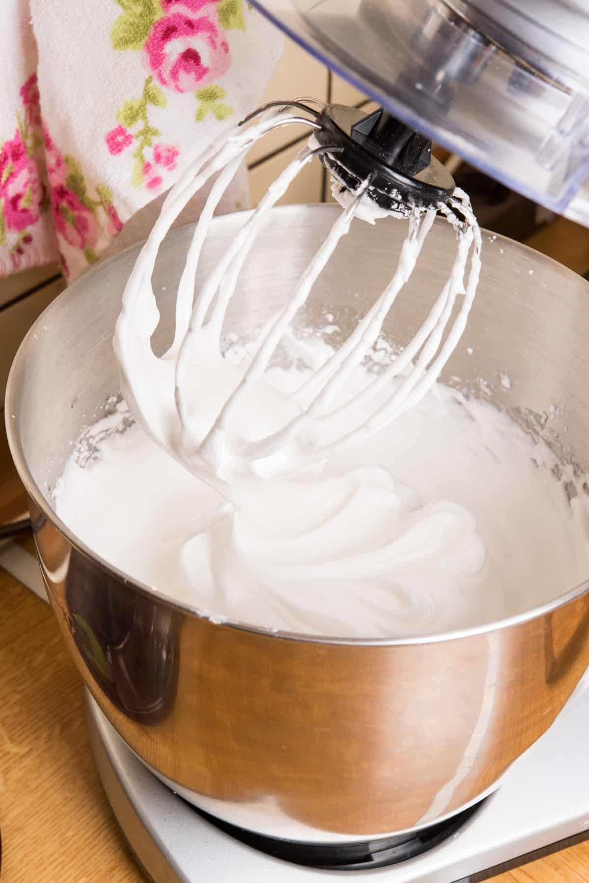 Whipped cream icing in a bowl with a whisk.