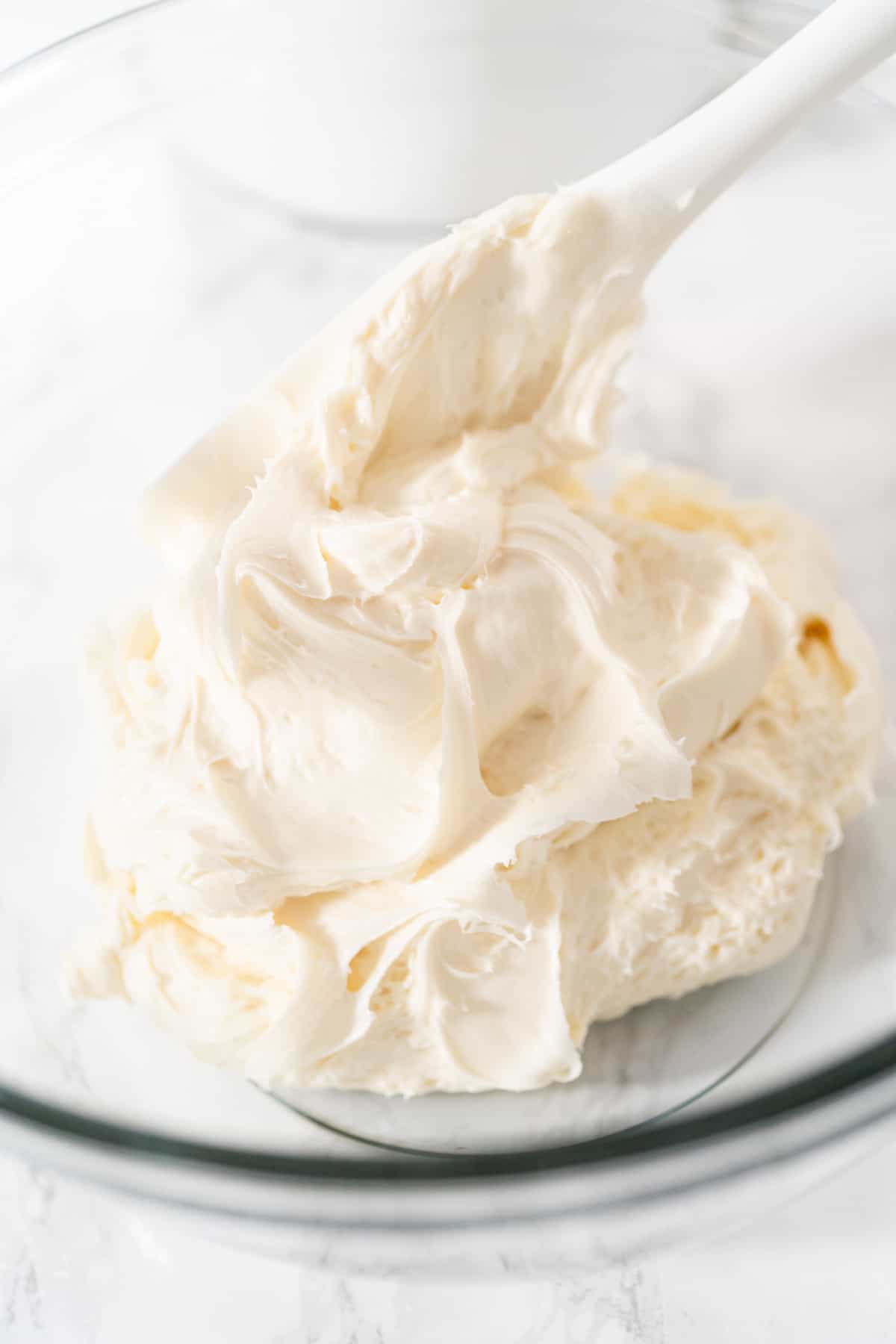 Vanilla frosting in a bowl with a spoon.