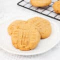 Three soft peanut butter cookies on a white plate.