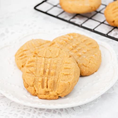 Three soft peanut butter cookies on a white plate.