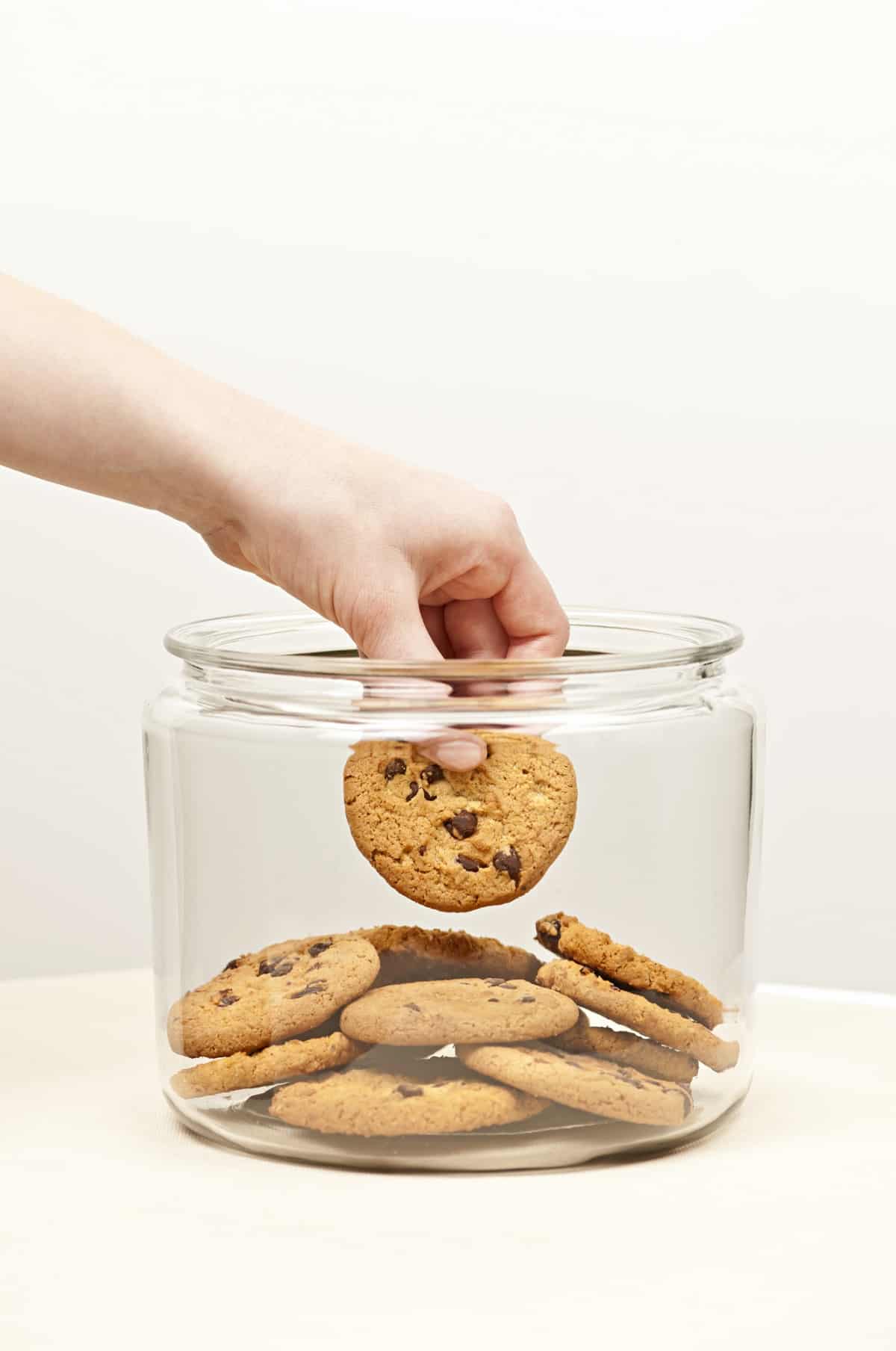 Chocolate chip cookies in a jar with a hand.