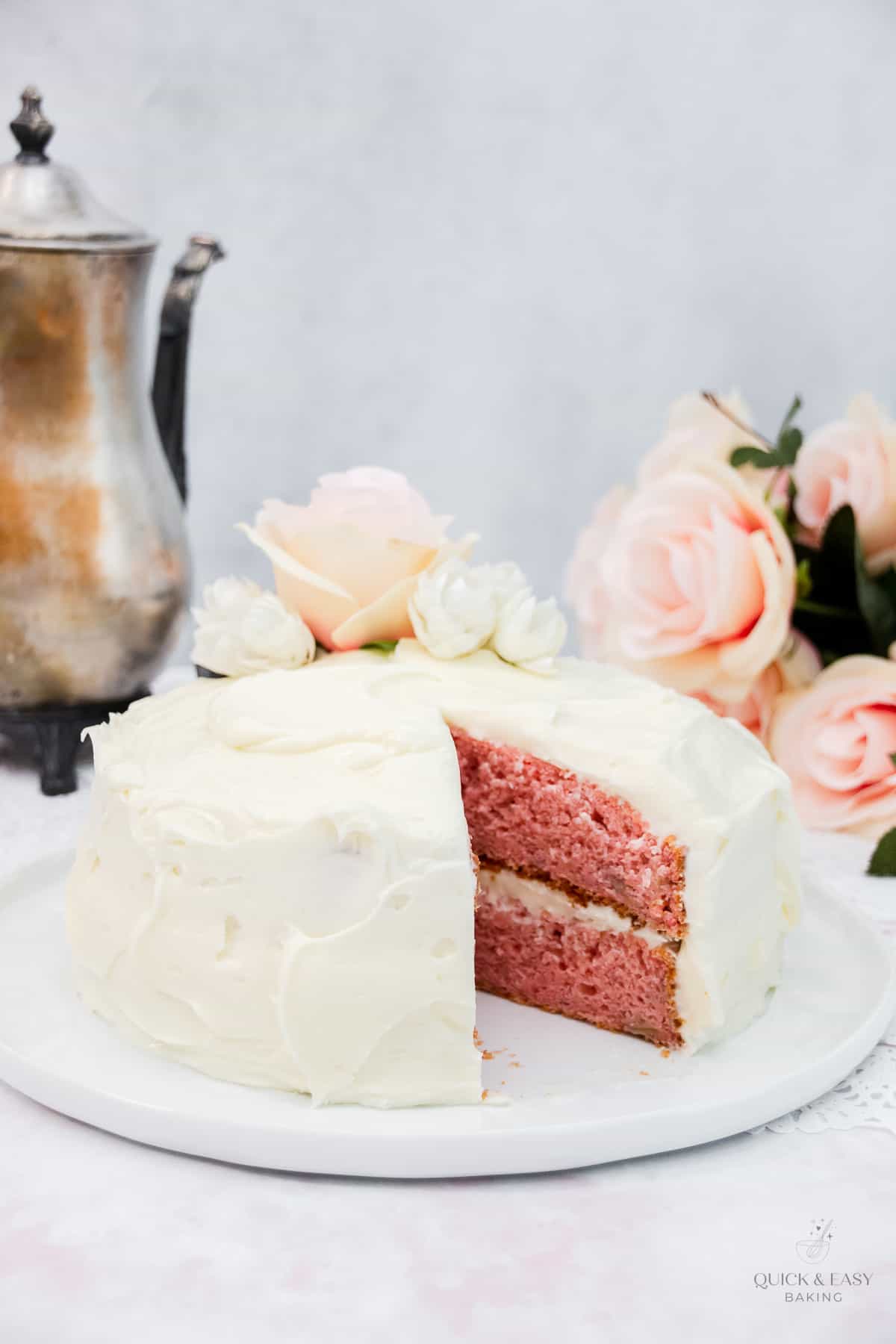 Decorated pink cake with white frosting and flowers.