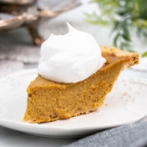 Large slice of pumpkin pie on a white plate.