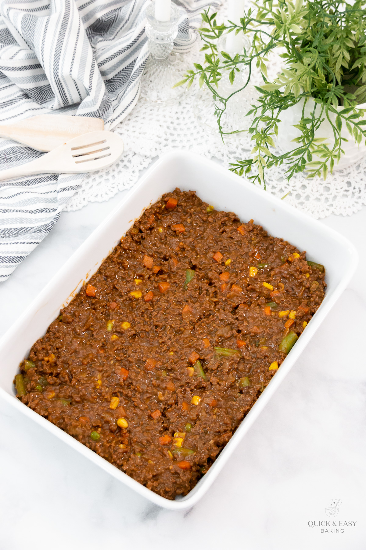 Beef mixture with gravy and vegetables in a white casserole dish.