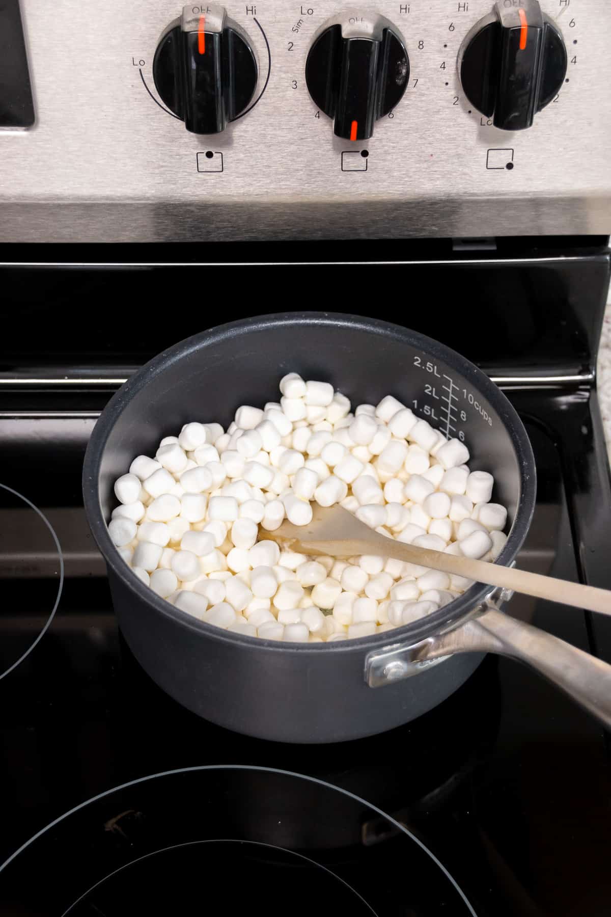 Marshmallows and butter in a small saucepan with a wooden spoon.