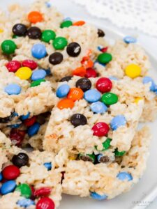 Squares of rice crispy treats with m&ms on a white platter.
