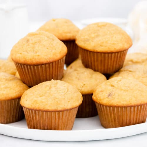 Wide image of stacked banana cake mix muffins on a white platter.
