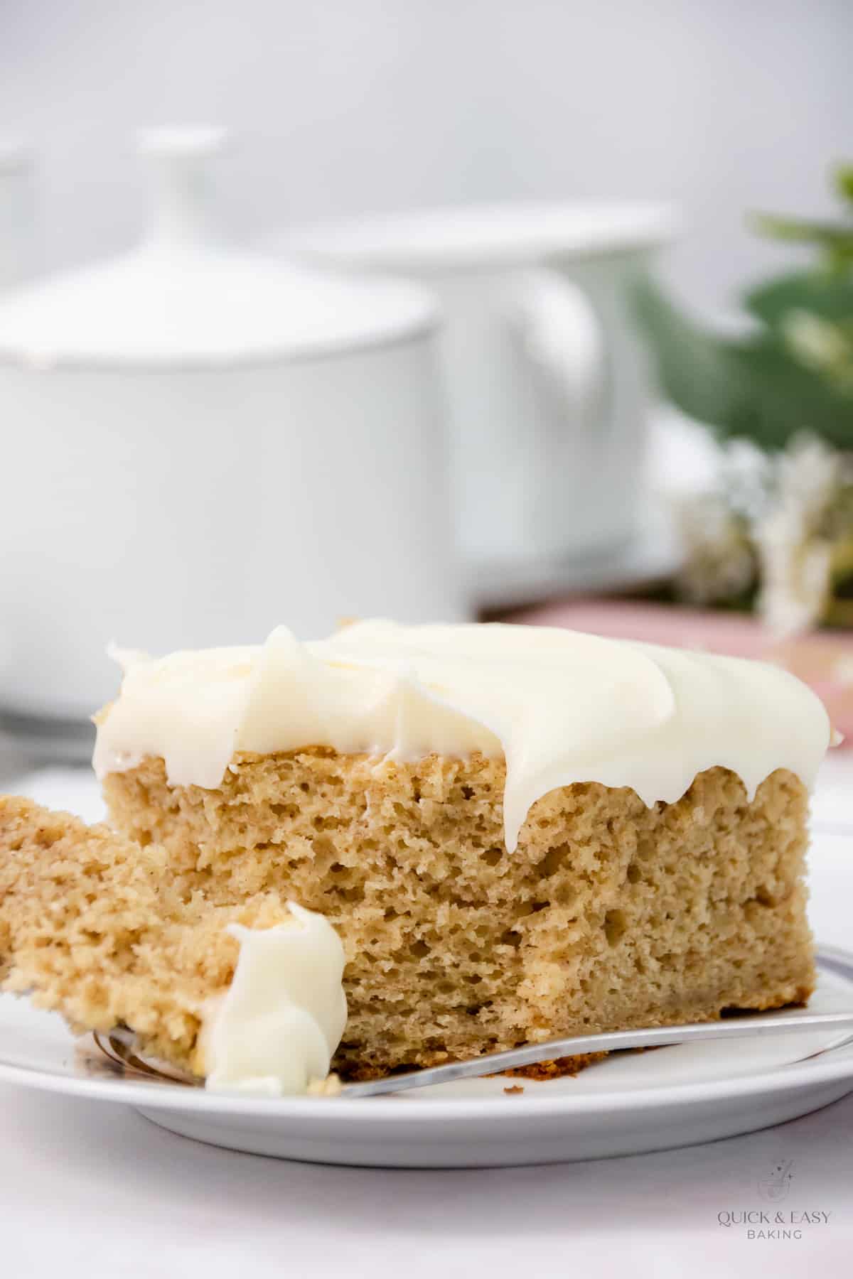 Large slice of banana bars with icing with a fork cutting a piece off.