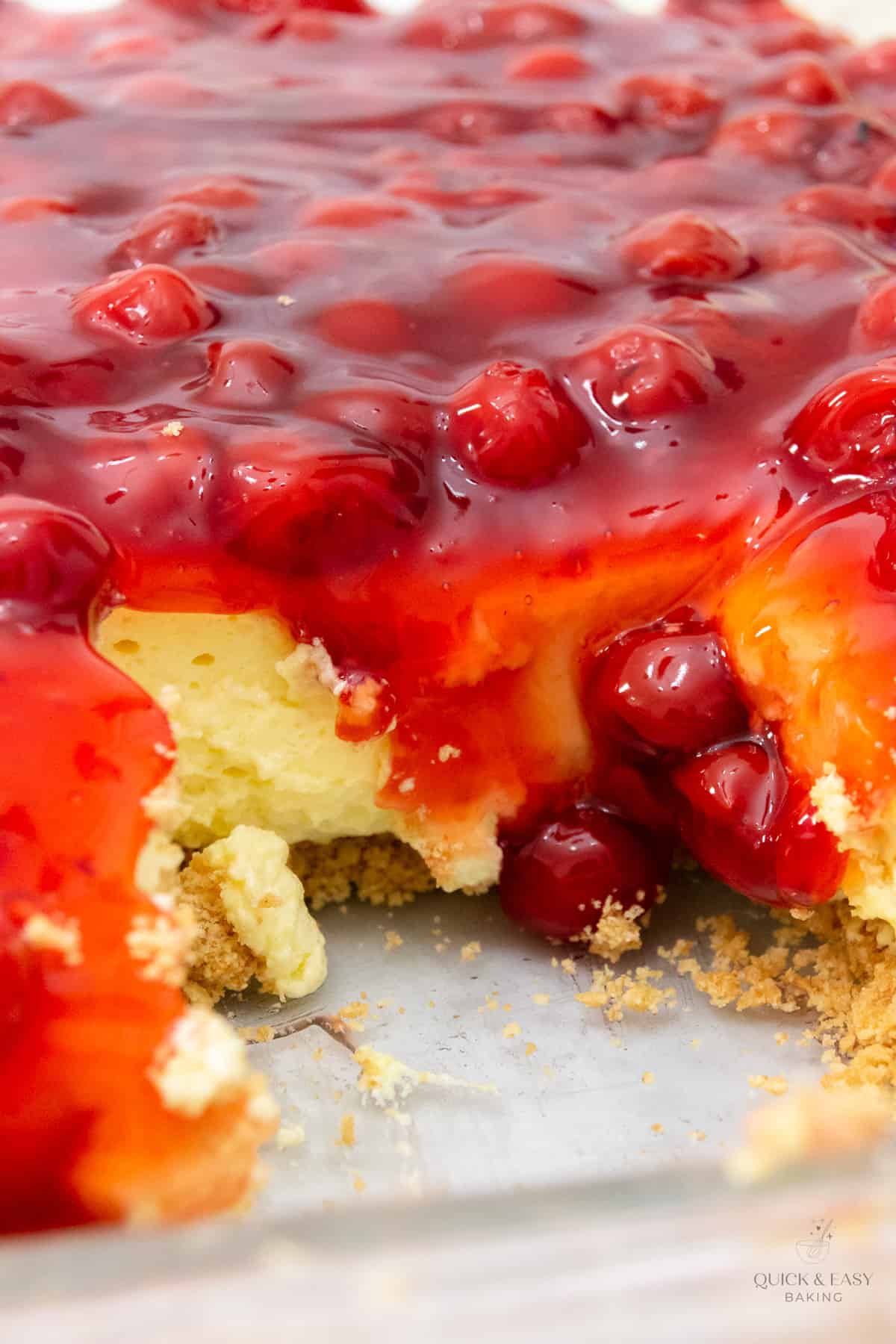 Close up of cheesecake in a baking dish with cherries covering it.