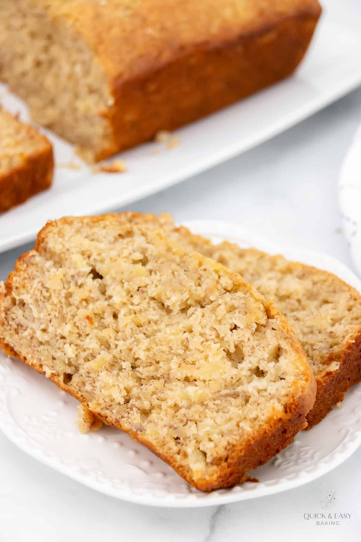 Close up view of sliced banana bread on a white plate.