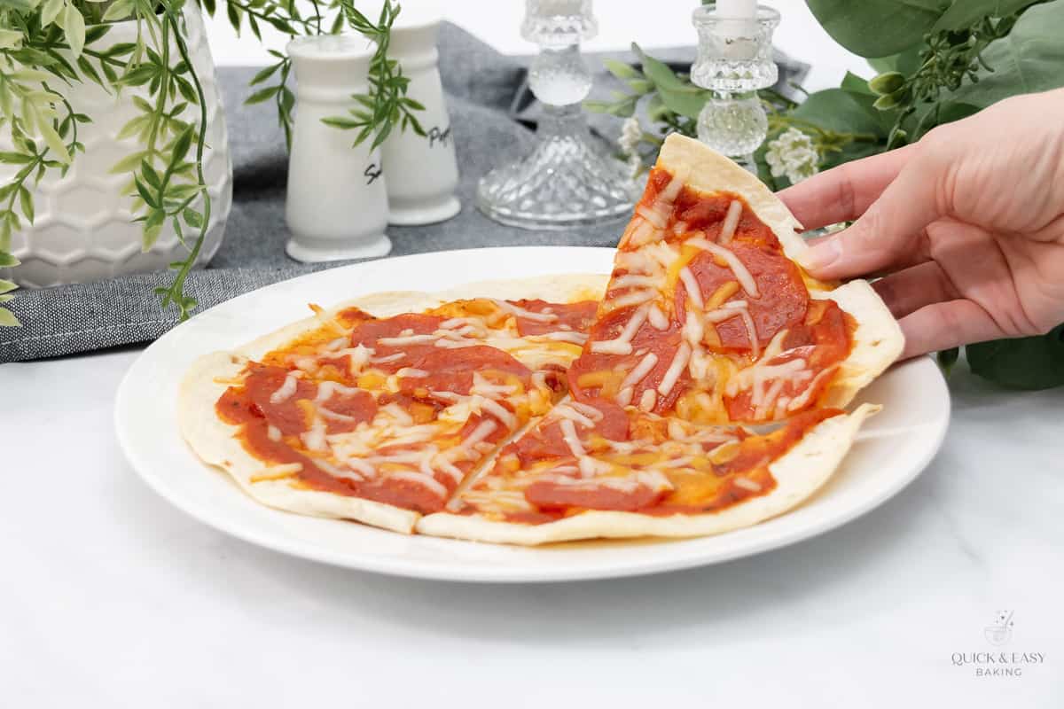 Wide image of homemade mini pizza using a flour tortilla with a white plate.