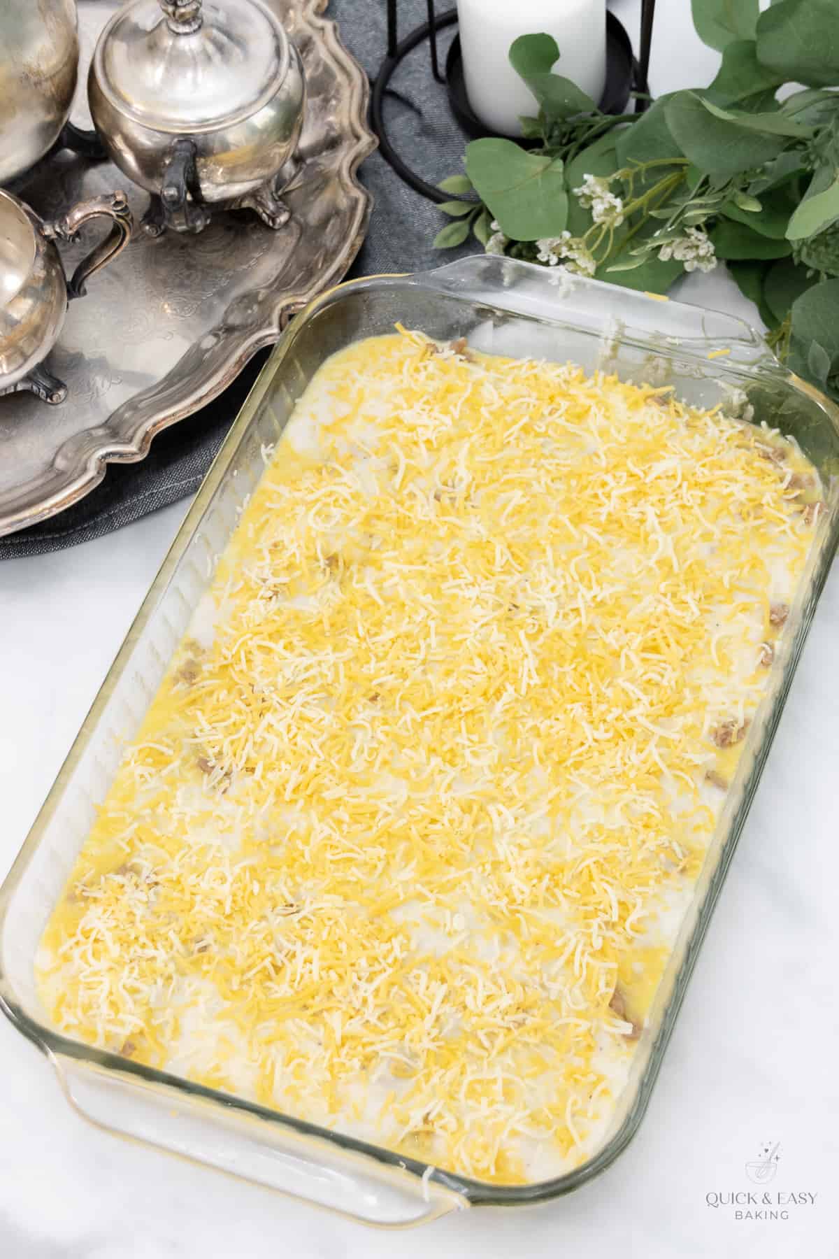 Shredded cheese spread over the top of the unbaked breakfast casserole.