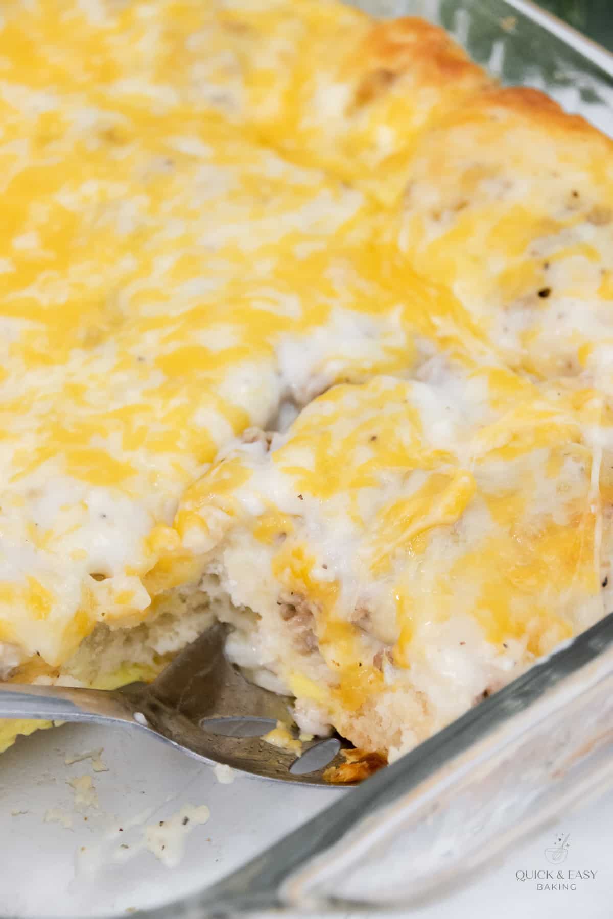 Slice of breakfast casserole with cheese in a baking dish.