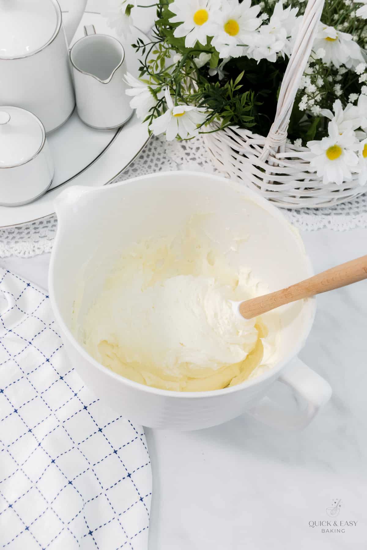 Cream cheese buttercream in a large white mixing bowl with a spatual.